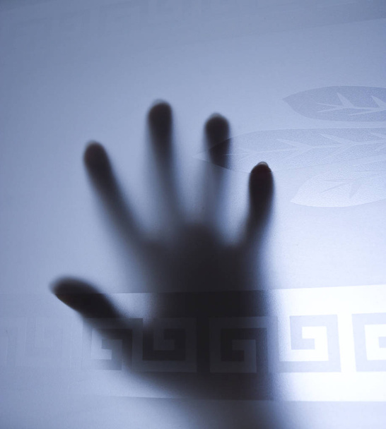 Focus selettivo - silhouette delle mani dietro una porta in vetro smerigliato. Il concetto di paura, gridare aiuto, pericolo
. - Foto, immagini