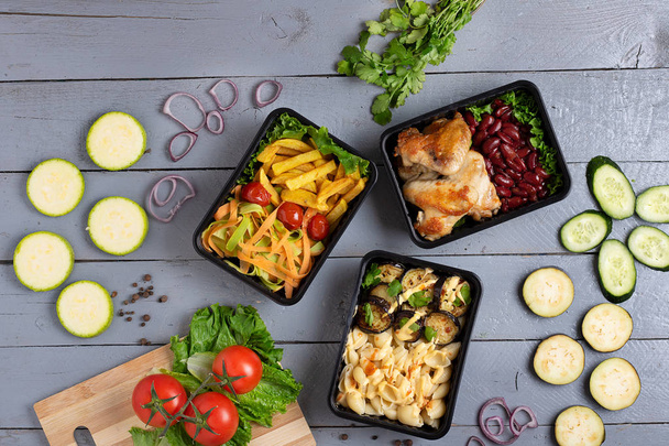 ylhäältä näkymä vihanneksia, kanankoipia, papuja, ranskalaisia perunoita, salaatti, nuudelit, munakoiso konteissa, terveellinen lounas  - Valokuva, kuva