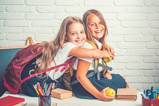 Little girls eat apple at lunch break. little girls eambrace at school lesson. - Photo, Image