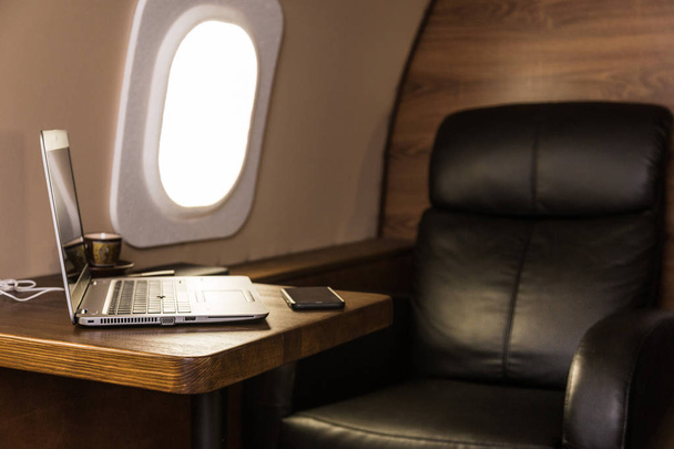 laptop on the table in the interior of a private jet. Flying first class. - Foto, imagen