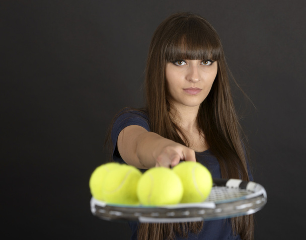 Female tennis player with racket and ball on black background - Foto, imagen