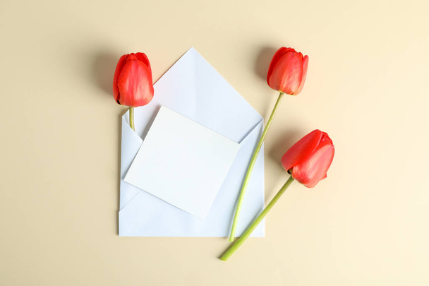 Envelope with space for text  and beautiful red tulips on color  - Photo, Image