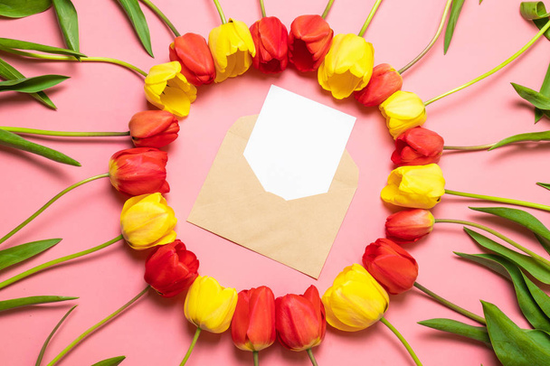 Vista superior do envelope e quadro de tulipas vermelhas no fundo rosa
. - Foto, Imagem
