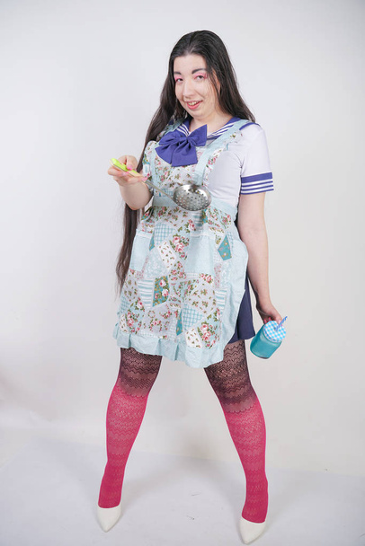 γοητευτική μελαχρινή Μαγειρική κορίτσι σε anime σχολική στολή και ποδιά κουζίνας σε λευκό φόντο στο στούντιο - Φωτογραφία, εικόνα