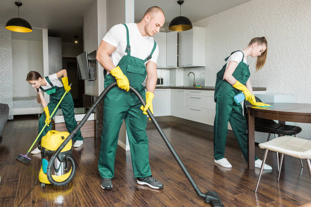 Cleaning service with professional equipment during work. professional kitchenette cleaning, sofa dry cleaning, window and floor washing. man and women in uniform, overalls and rubber gloves - Photo, Image