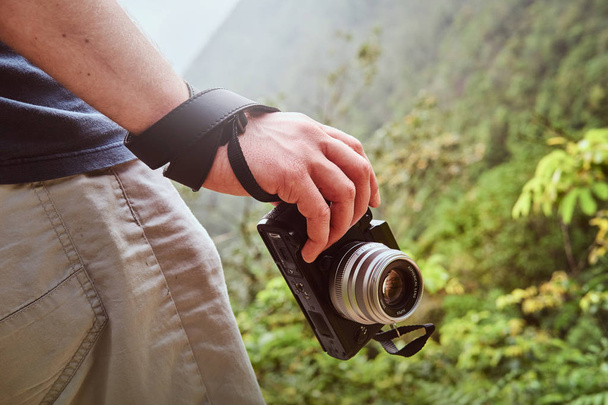 Az ember tartja kamera a kezében járás közben az ösvényen dobja a zöld hegyek - Fotó, kép