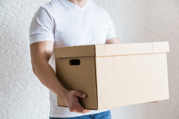 Delivery strong, muscular man loading cardboard boxes for moving to an apartment. professional worker of transportation, male loaders in overalls. free space for text, isolated - Fotó, kép