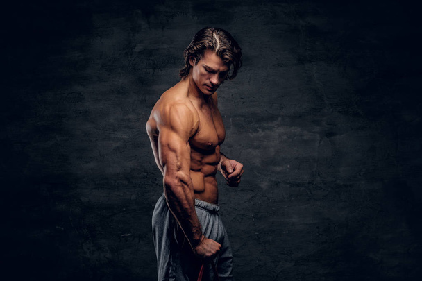 Atractivo culturista sin camisa está posando con goma y mostrando sus músculos
 - Foto, imagen