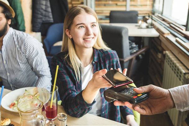 Young attractive woman paying in cafe with contactless smartphone payment - Foto, Imagem