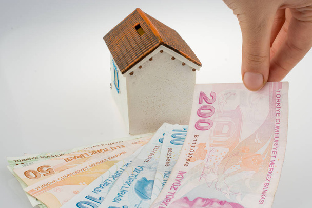 Ręczne trzymanie banknotów tureckiej liry przy boku modelowego domu na białym tle - Zdjęcie, obraz