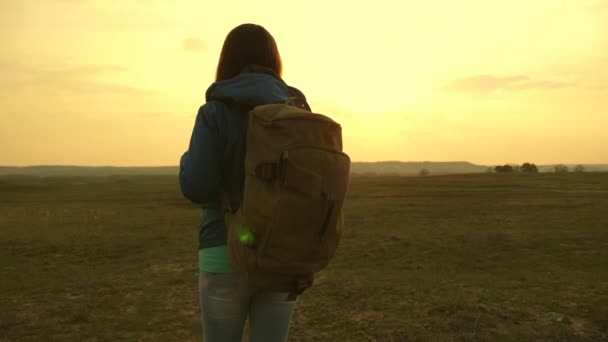 tourist young woman goes on a sunset to the mountains. girl traveling with a backpack against the sky and the flare of the sun. desire for knowledge of the world. sports tourism concept. - Footage, Video