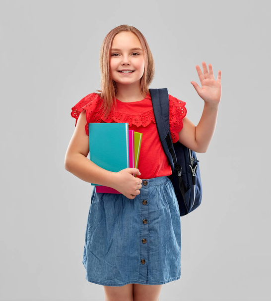happy student girl with books and bag waving hand - Фото, изображение