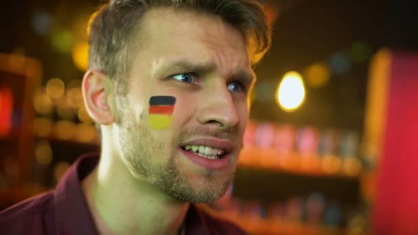 Abanico masculino decepcionado con bandera alemana pintada en la mejilla agitando la mano, fracaso
 - Imágenes, Vídeo