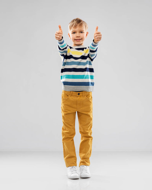 smiling boy in striped pullover showing thumbs up - Fotó, kép