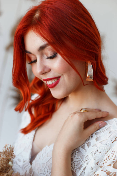 Wedding content - close-up Portrait of a young beautiful redhair girl in a studio standing on a white background with a decorations. Copy space - Photo, image