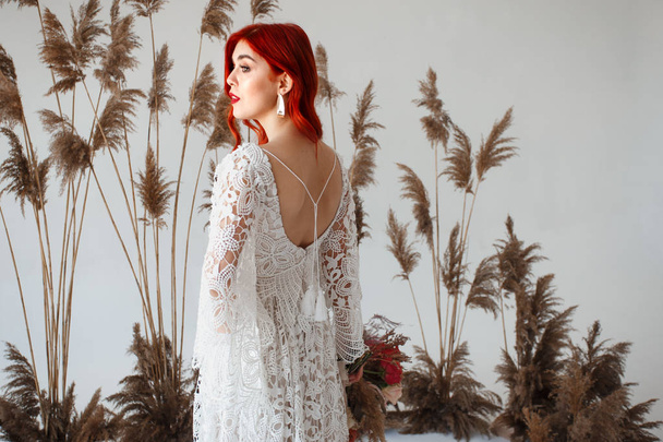 Wedding content - close-up Portrait of a young beautiful redhair girl in a studio standing on a white background with a decorations. Copy space - Photo, Image