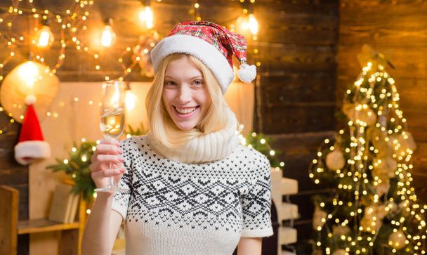 Attractive woman in a Christmas room with champagne in her hands. Blonde girl. Cheers. - Fotó, kép