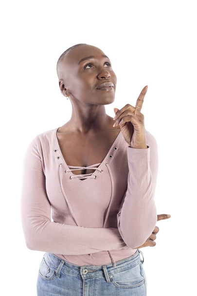 Black african american female model with bald hairstyle wearing a pink shirt on a white background advertising or presenting something. - Foto, afbeelding