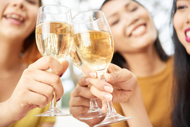 Primer plano de copas con champán sosteniendo por mujeres jóvenes felices, brindan y celebran la fiesta
 - Foto, Imagen