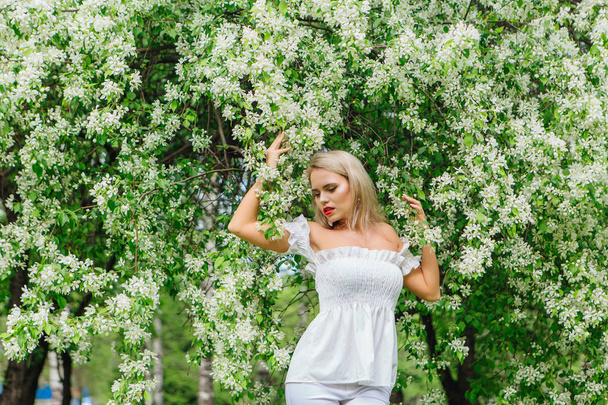 セクシーな近代的な花嫁は、咲くリンゴの木の花を楽しみます. - 写真・画像