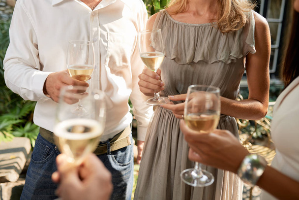 Gli ospiti che bevono vino bianco e chattano alla festa all'aperto
 - Foto, immagini