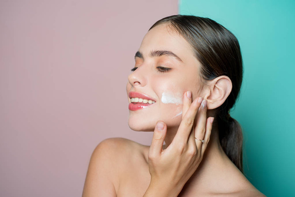 Facial care for female. Keep skin hydrated regularly moisturizing cream. Fresh healthy skin concept. Taking good care of her skin. Beautiful woman spreading cream on her face. Skin cream concept - Photo, Image