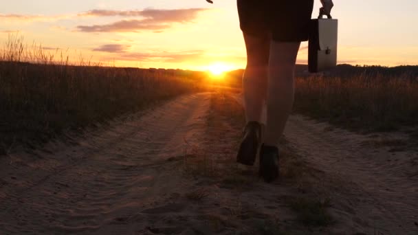 Egy üzletasszony sétál egy ország úton a tabletta a kezében, a nap miertsaet, női lábak között. szexi üzleti nő lány fut a vidéken. szexi lány utazik a vidéki - Felvétel, videó