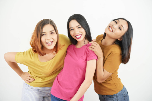 Image de jeunes femmes heureuses multiraciales souriant à la caméra tout en se tenant sur fond blanc
 - Photo, image