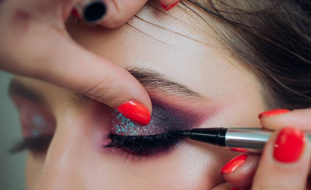 Close-up portrait. Process of making makeup. A professional make-up artist paints eyelashes models in the studio. - Fotoğraf, Görsel