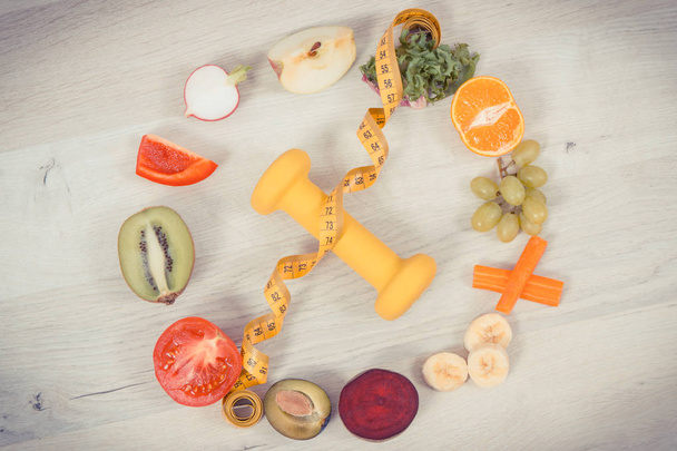 Фуиты и овощи, гантели и лента мера, концепция питательной пищи, здорового образа жизни и похудения
 - Фото, изображение