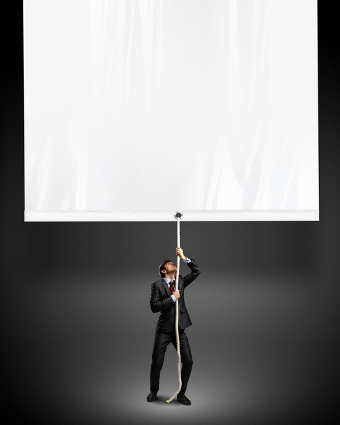 Businessman pulling blank banner - Fotó, kép