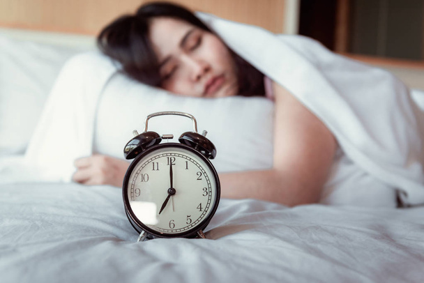 Pretty Young Woman is Sleeping and Alarm Clock in Bedroom, Beautiful Girl is Sleeping on Her Bed and Relaxing in The Morning., Healthcare and Lifestyles Concept. - Photo, Image
