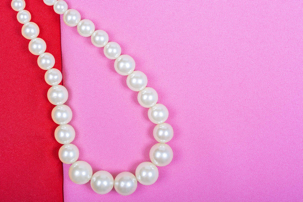 Background of red and pink fabric, the necklace from the pearls. Place for text, top view, Lay Flat, Copy space. - Photo, Image
