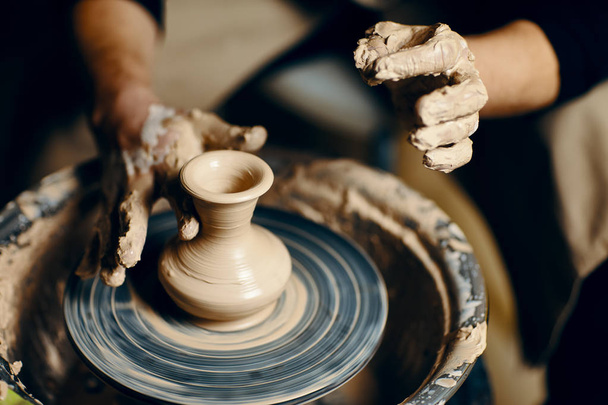 Man potter working on potters wheel making ceramic pot from clay in pottery workshop. art concept - Foto, Bild