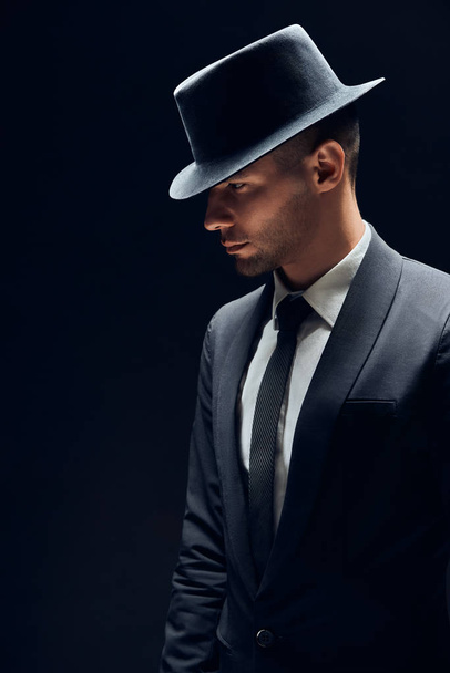Profile view portrait oh handsome man in black suit and hat on dark background. Man beauty concept                                          - Φωτογραφία, εικόνα
