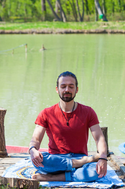 νεαρός άνδρας πρακτική γιόγκα καλοκαιρινή μέρα στη λίμνη διαλογίζονται - Φωτογραφία, εικόνα