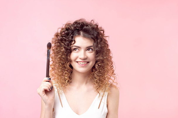 Cheerful happy woman sitting with a makeup brush while working in the beauty salon - Foto, Imagen