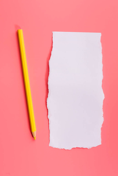 A piece of white torned paper over pink background with pencil - Φωτογραφία, εικόνα