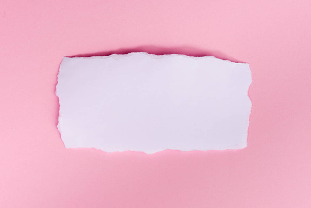 A piece of white torned paper over pink background  - Valokuva, kuva