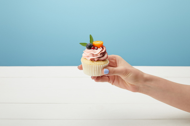 cropped view of woman holding sweet cupcake isolated on blue - Fotoğraf, Görsel
