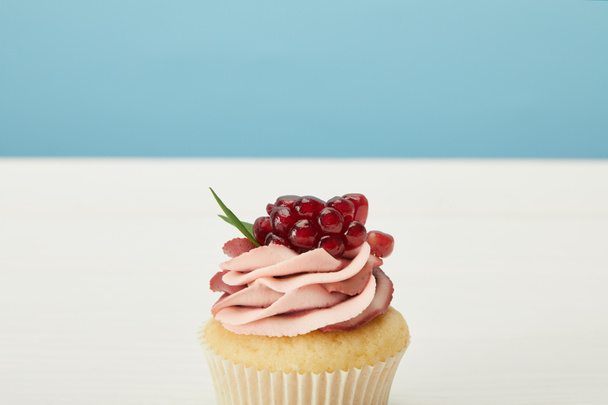 sabroso cupcake con granate y crema en la superficie blanca aislado en azul
 - Foto, imagen