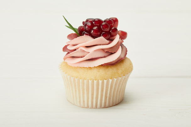 tasty cupcake with cream and garnet on white surface - Foto, Bild