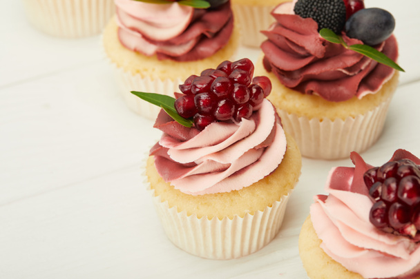 selective focus of cupcakes with cream and berries on white surface - Photo, Image