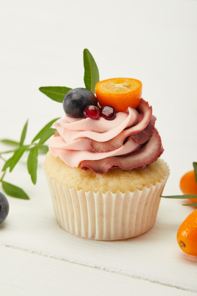 cupcake with cream and kumquats on white surface - Photo, Image
