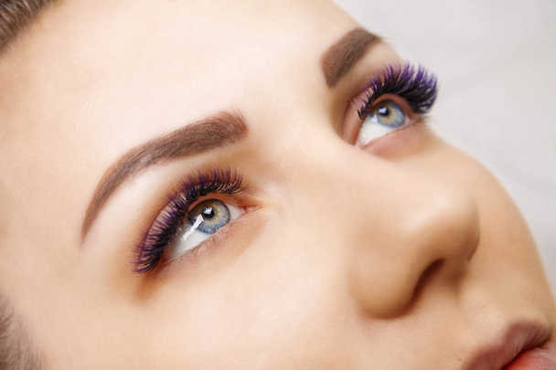 Eyelash Extension Procedure. Woman Eye with Long Blue Eyelashes. Ombre effect. Close up, selective focus. - Photo, Image