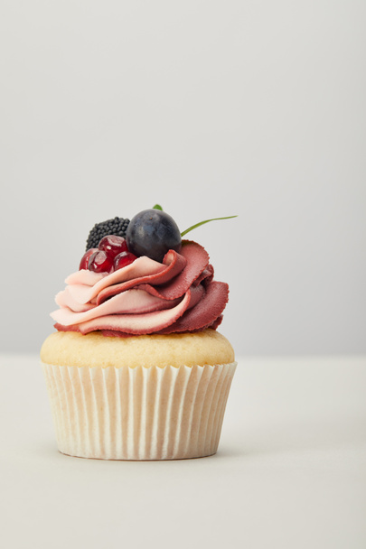 cupcake with cream, garnet, grape and blackberry isolated on grey - Foto, Imagem