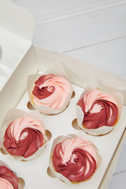 cupcakes with cream in box on white wooden surface - Foto, Imagem