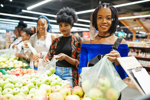 Group of five african womans picking up apples in plastic bags a - Foto, immagini