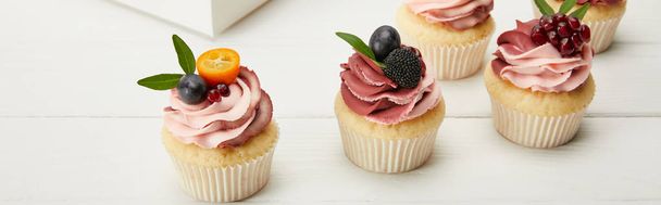 panoramic shot of cupcakes with fruits and berries on white surface - Photo, Image