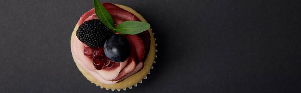 黒い表面にクリーム、ガーネット、ブドウ、ブラックベリーとカップケーキのパノラマショット - 写真・画像